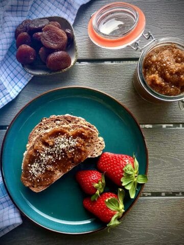 Jar of dried apricot chia jam next to a plate with toast.