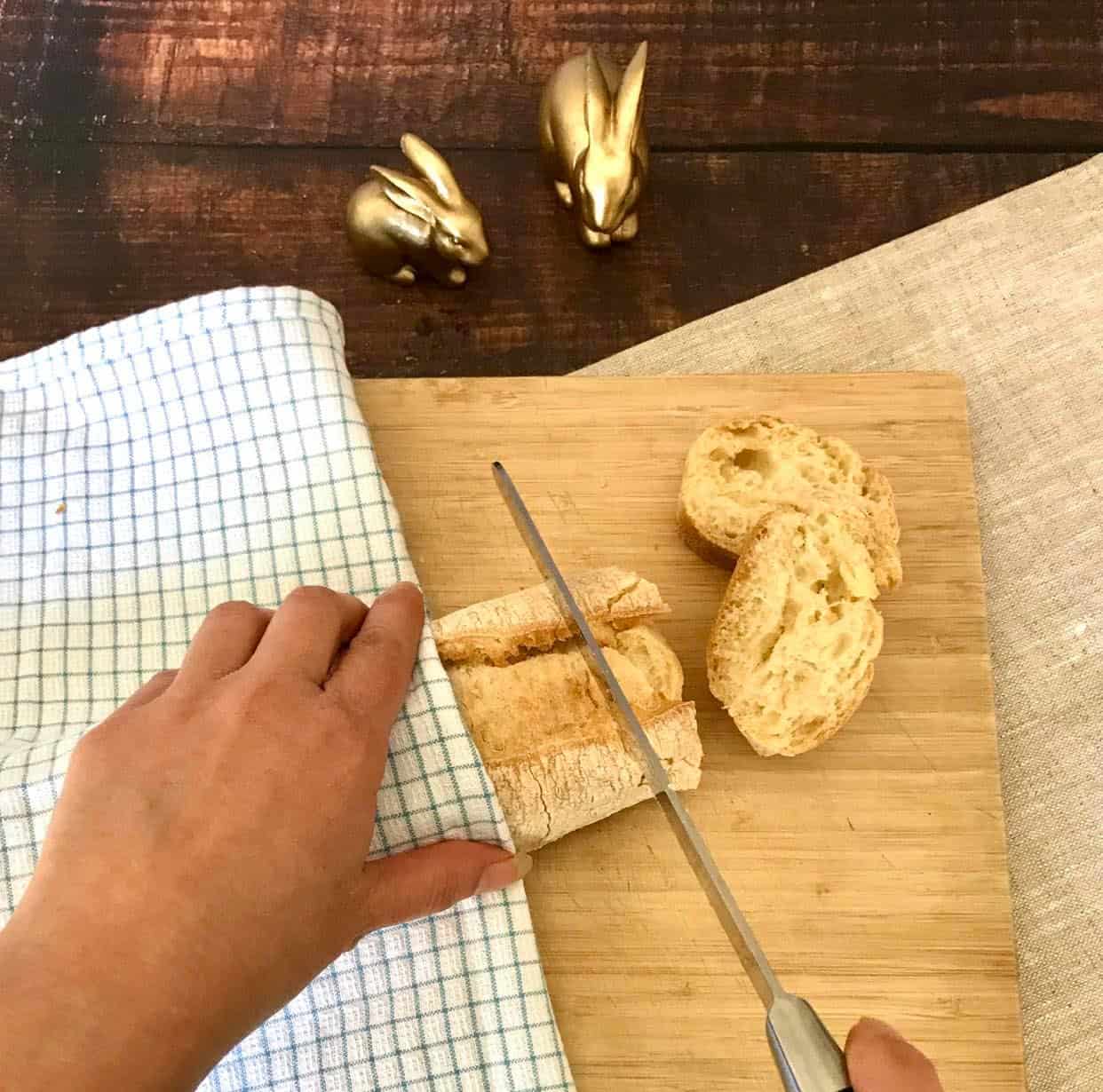Hand cutting a baguette into slices.