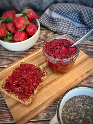 Chia berry jam in a jar next to a piece of bread with jam.