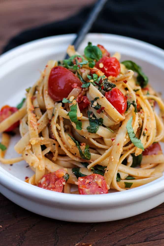 Vegan spinach tomato pasta in a bowl.