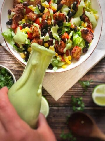 Vegan cilantro-lime dressing being poured over a salad.