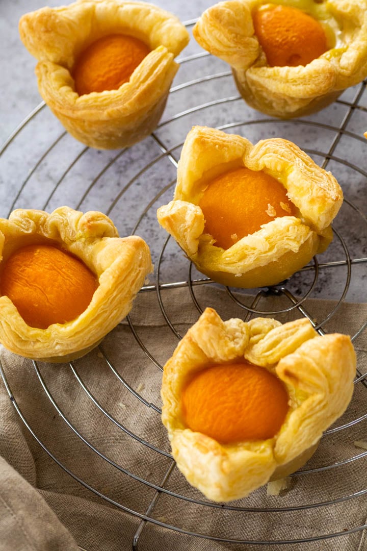 Vegan custard apricot tarts on a cooling rack.