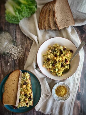 Chickpea salad in a bowl next to a sandwich.