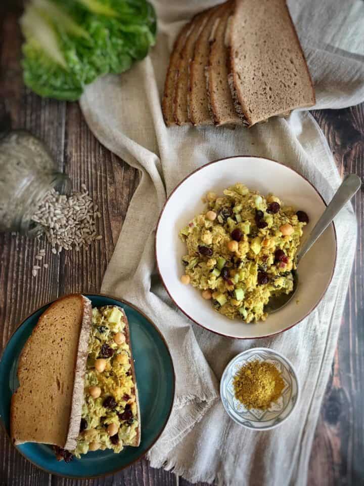 Chickpea salad in a bowl next to a sandwich.