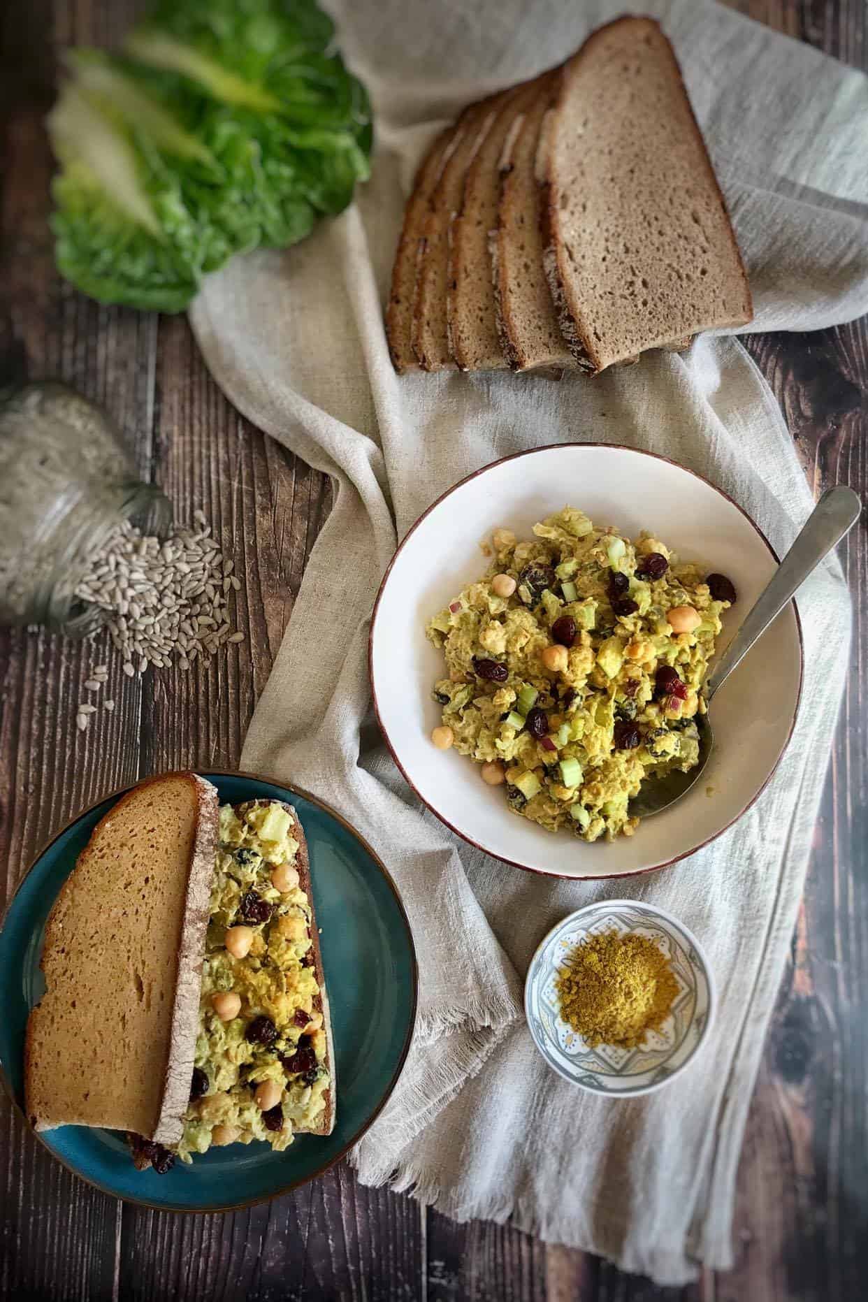 Chickpea salad in a bowl next to a sandwich.