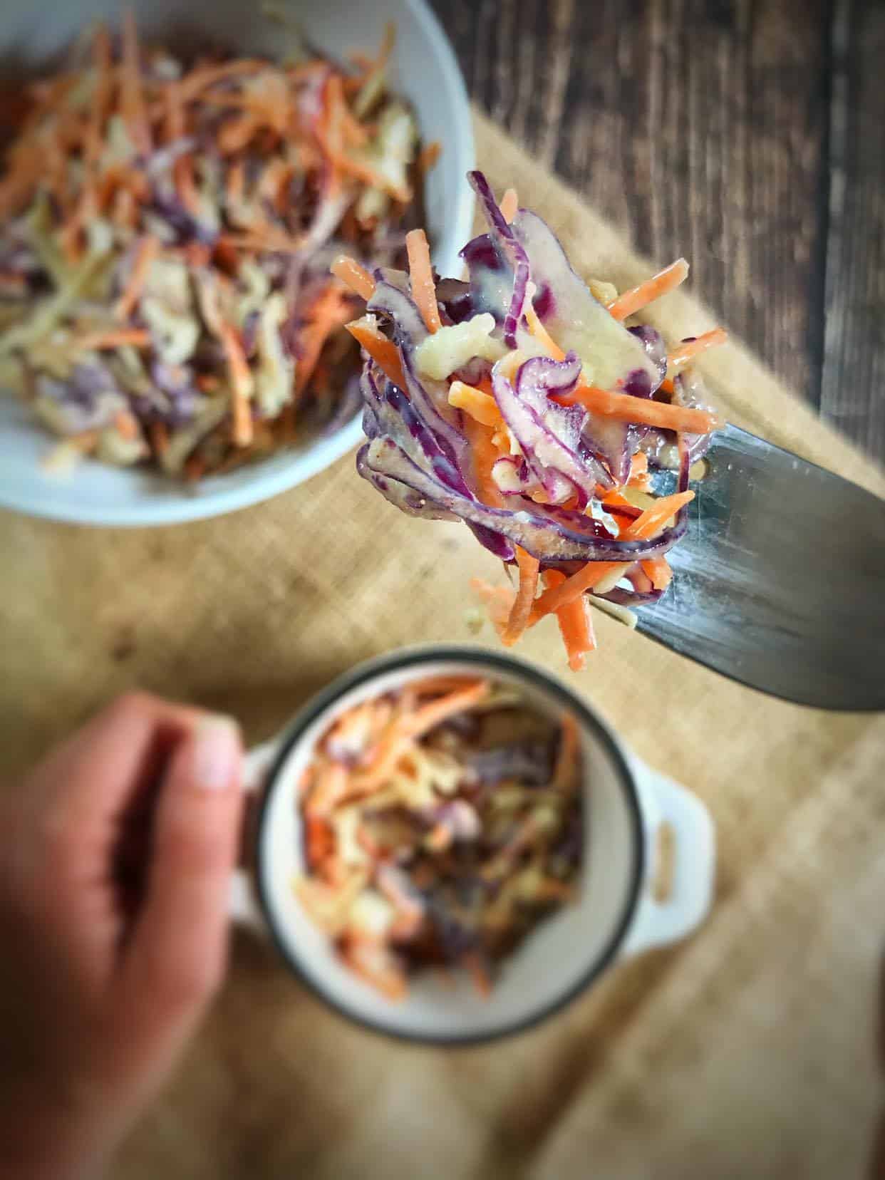 Hand lifting a fork of vegan coleslaw.
