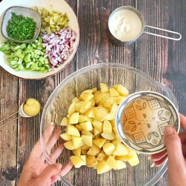Adding vinegar to cooked potatoes.
