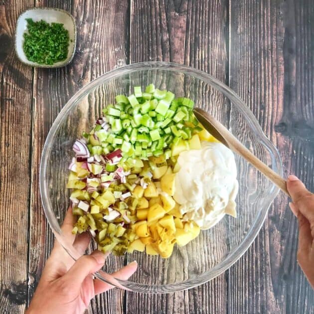Hand mixing up oil-free vegan potato salad.