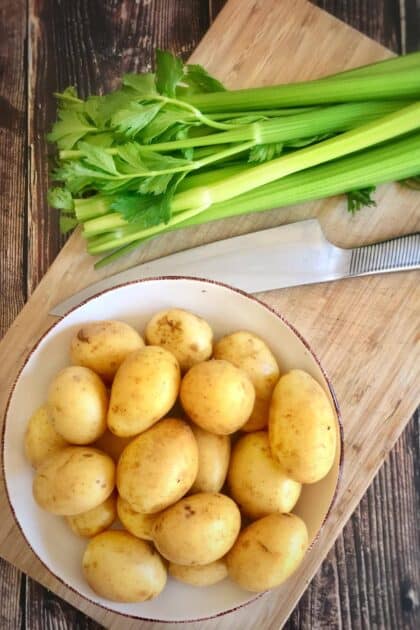 Potatoes and celery on a cutting board.