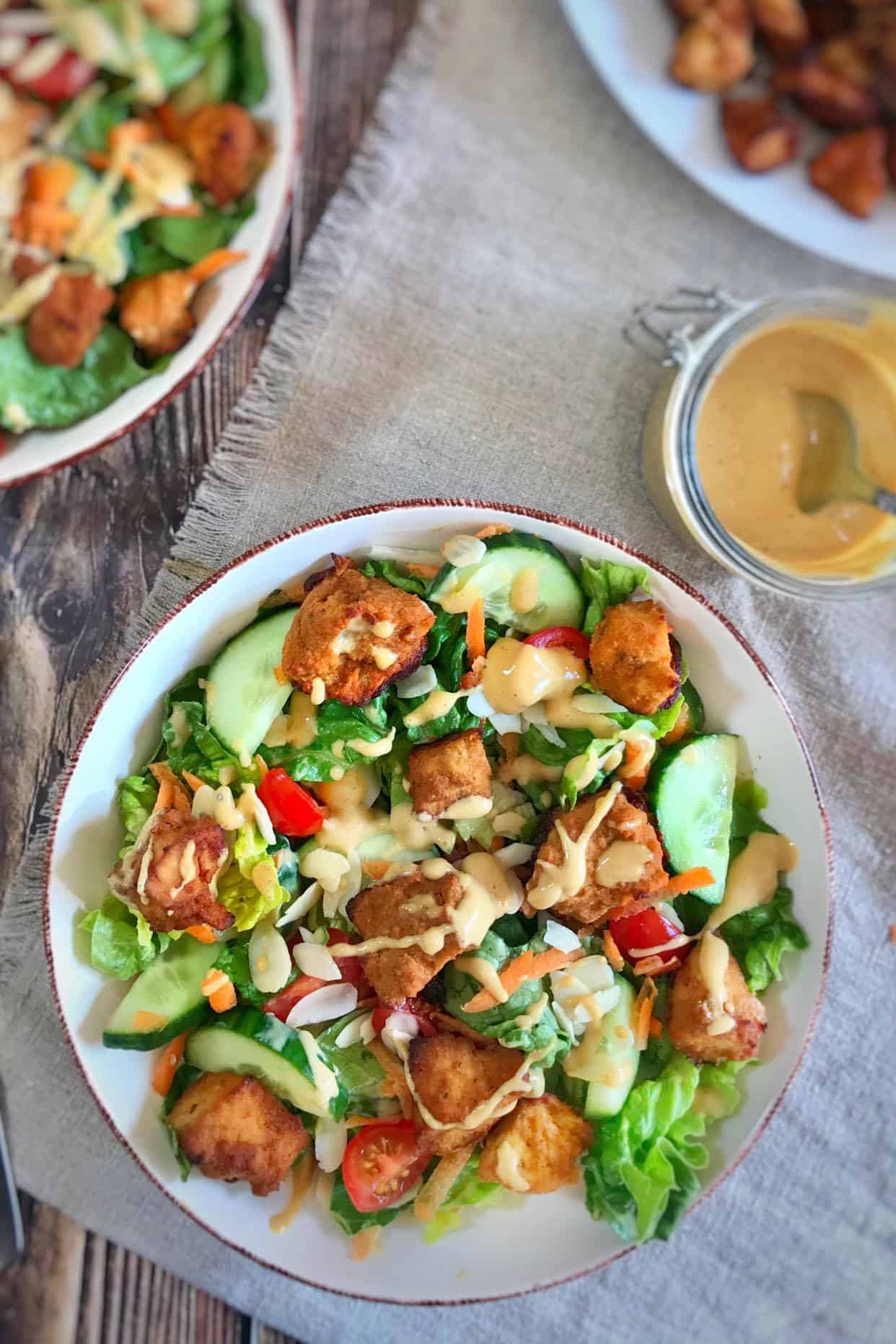 Crispy tofu salad topped with dressing.