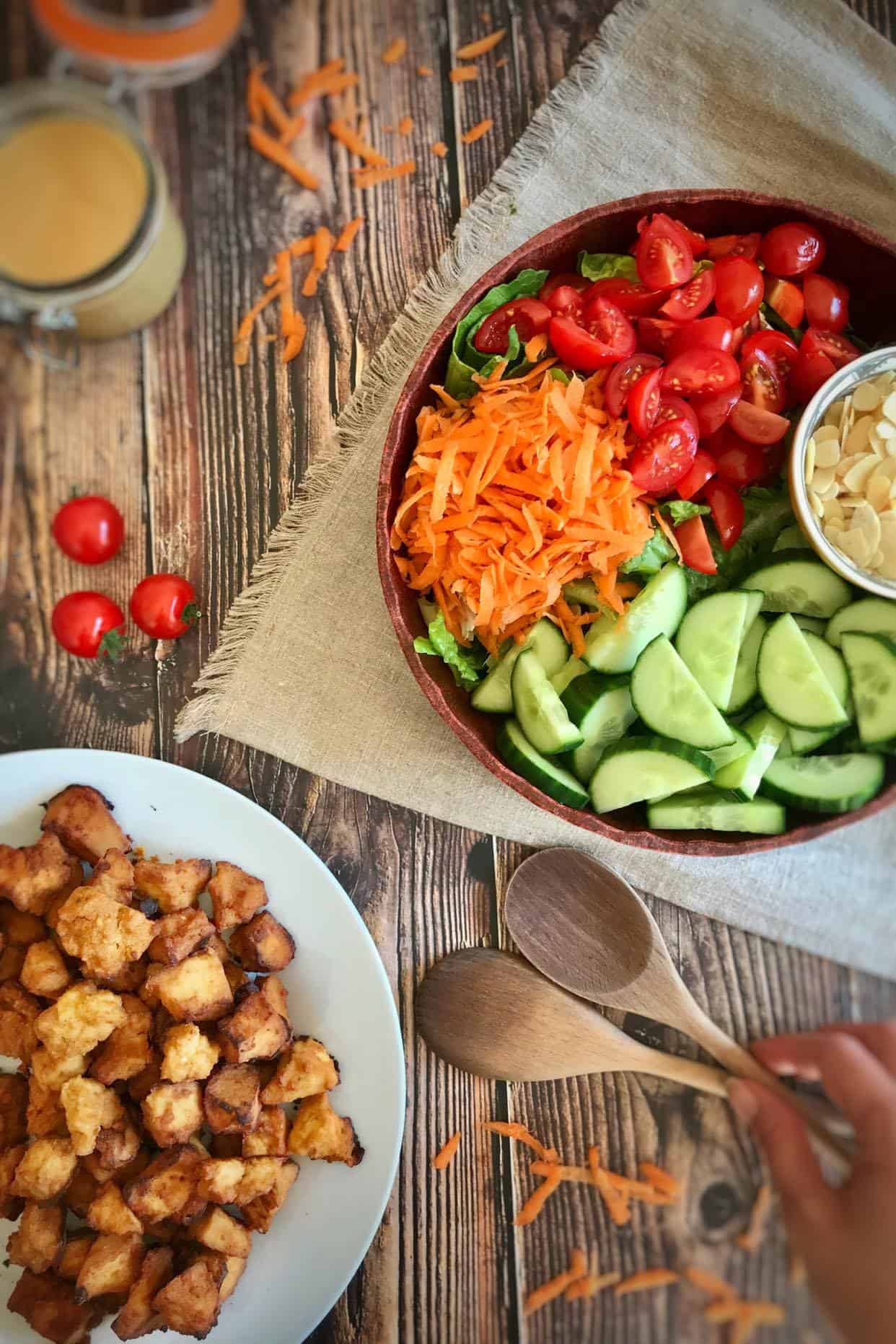 Salad in a bowl next to a plate of crispy tofu.