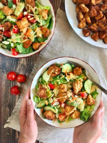Crispy tofu salad topped with vegan honey mustard dressing.