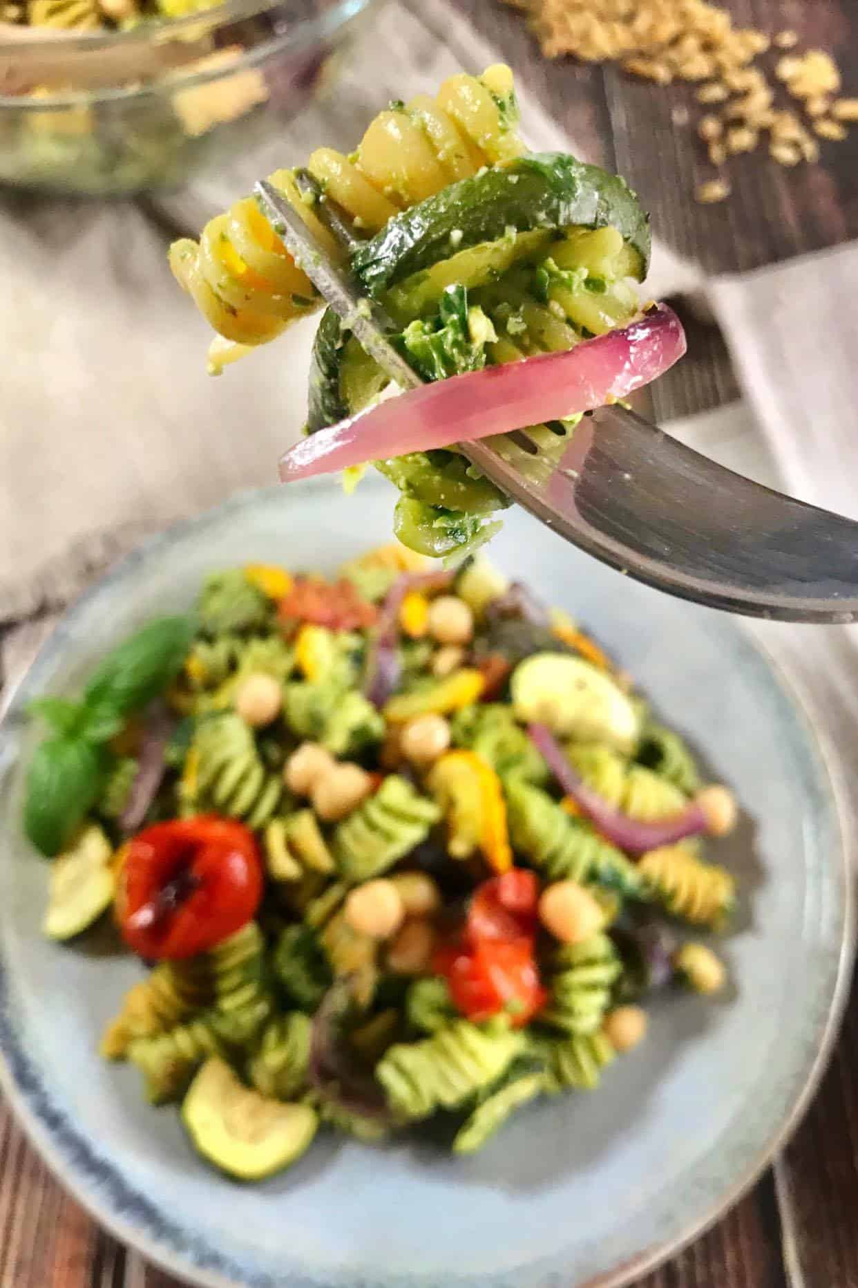 Fork picking up a bite of vegan pesto pasta salad.