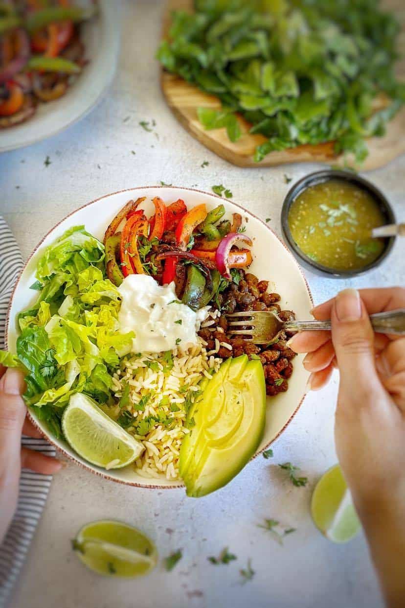 Hand holding a fork in a black bean burrito bowl.