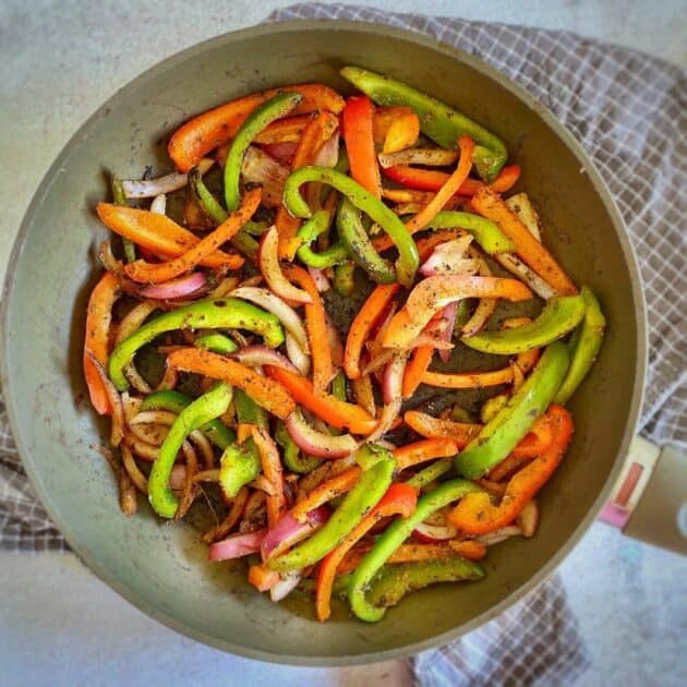 Cooked onions and peppers in a skillet.
