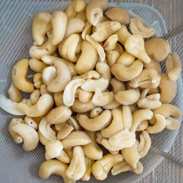 Boiled cashews in a strainer.