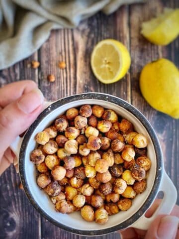 Hand holding a bowl of oil-free roasted chickpeas.