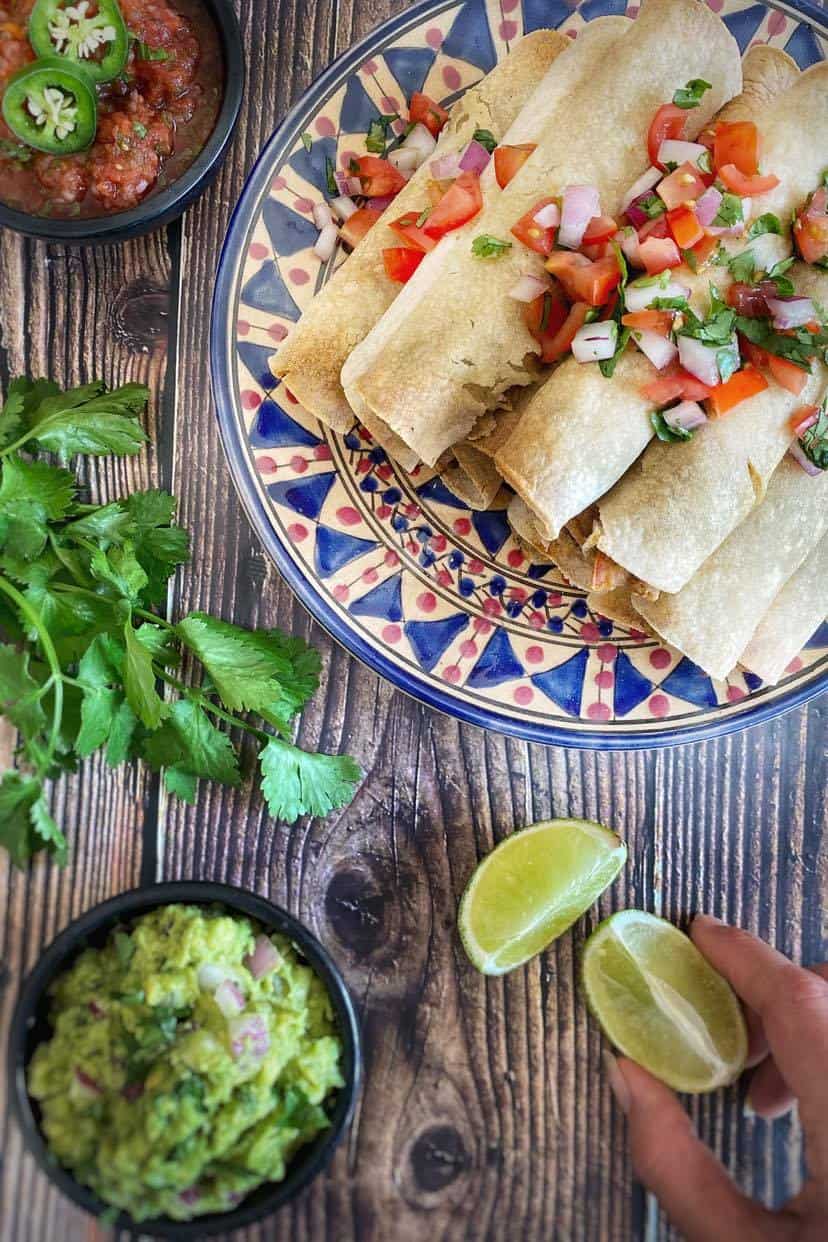 Vegan taquitos stacked on a plate.
