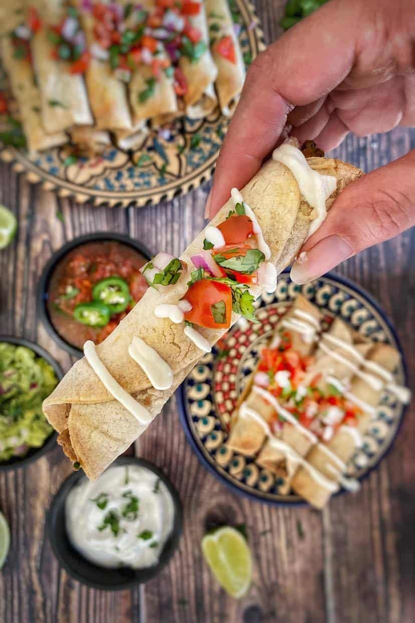 Hand holding up a vegan taquito.