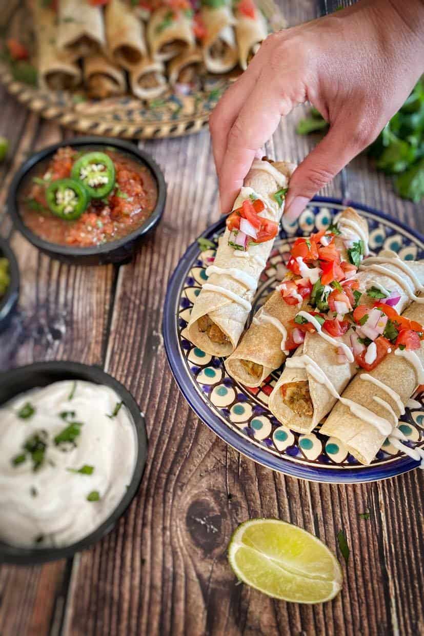 Hand picking up a vegan taquito.