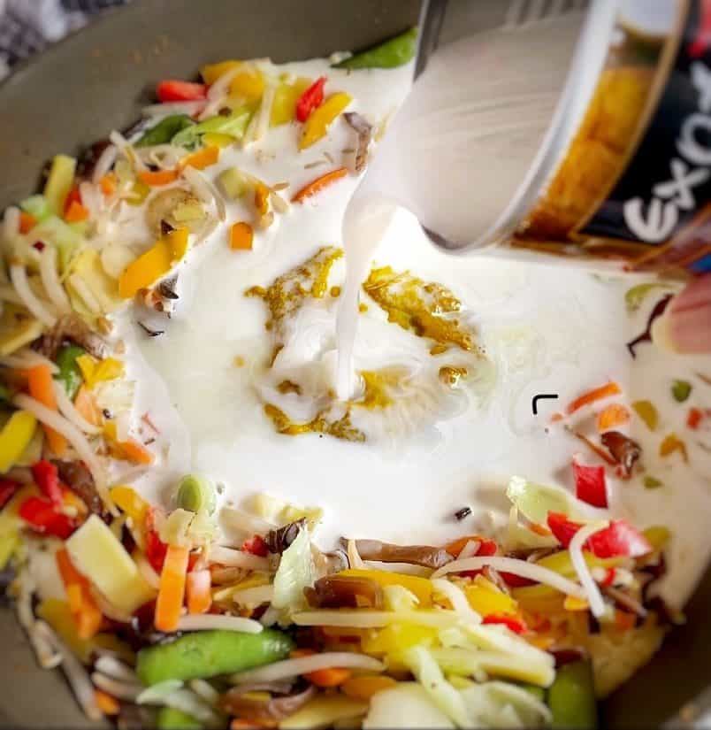 Adding coconut milk to Thai curry.