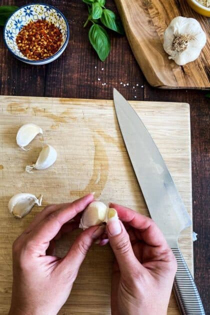 Hands peeling garlic.