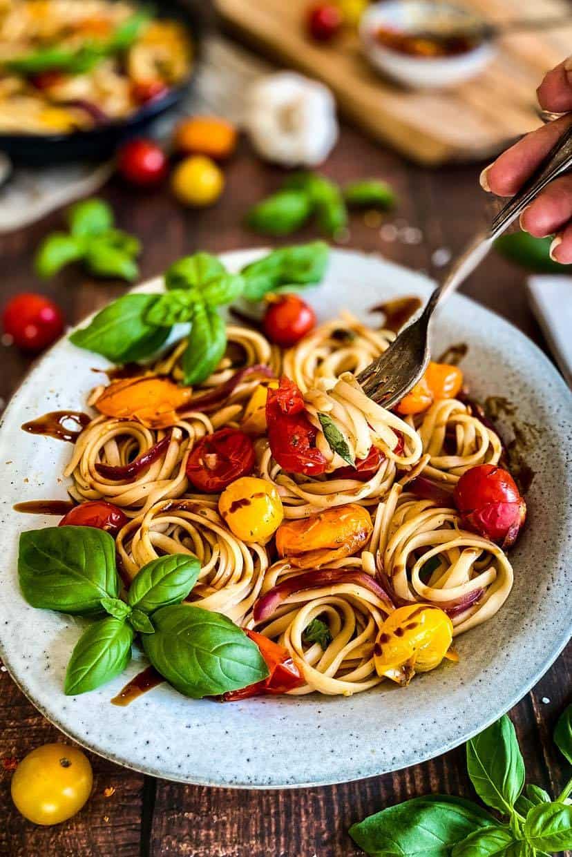 Plate of vegansk pasta with burst cherry tomato sauce.