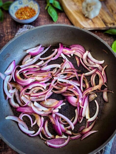 Red onion slices cooked in a skillet.