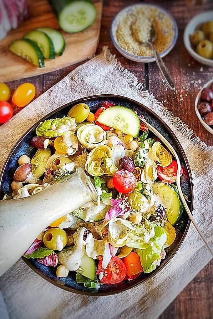 Creamy Italian dressing being poured over a salad.