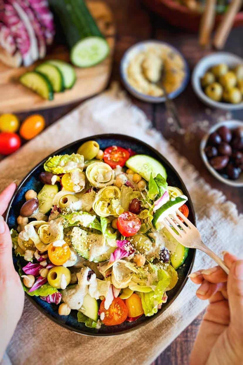 Hand lifting a forkful of vegan Italian salad.