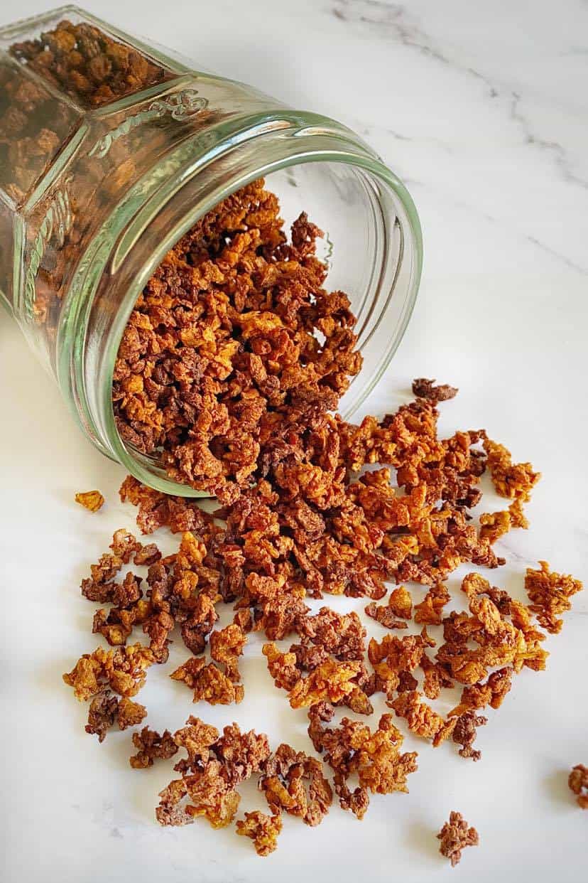 Vegan bacon bits spilling out of a jar.