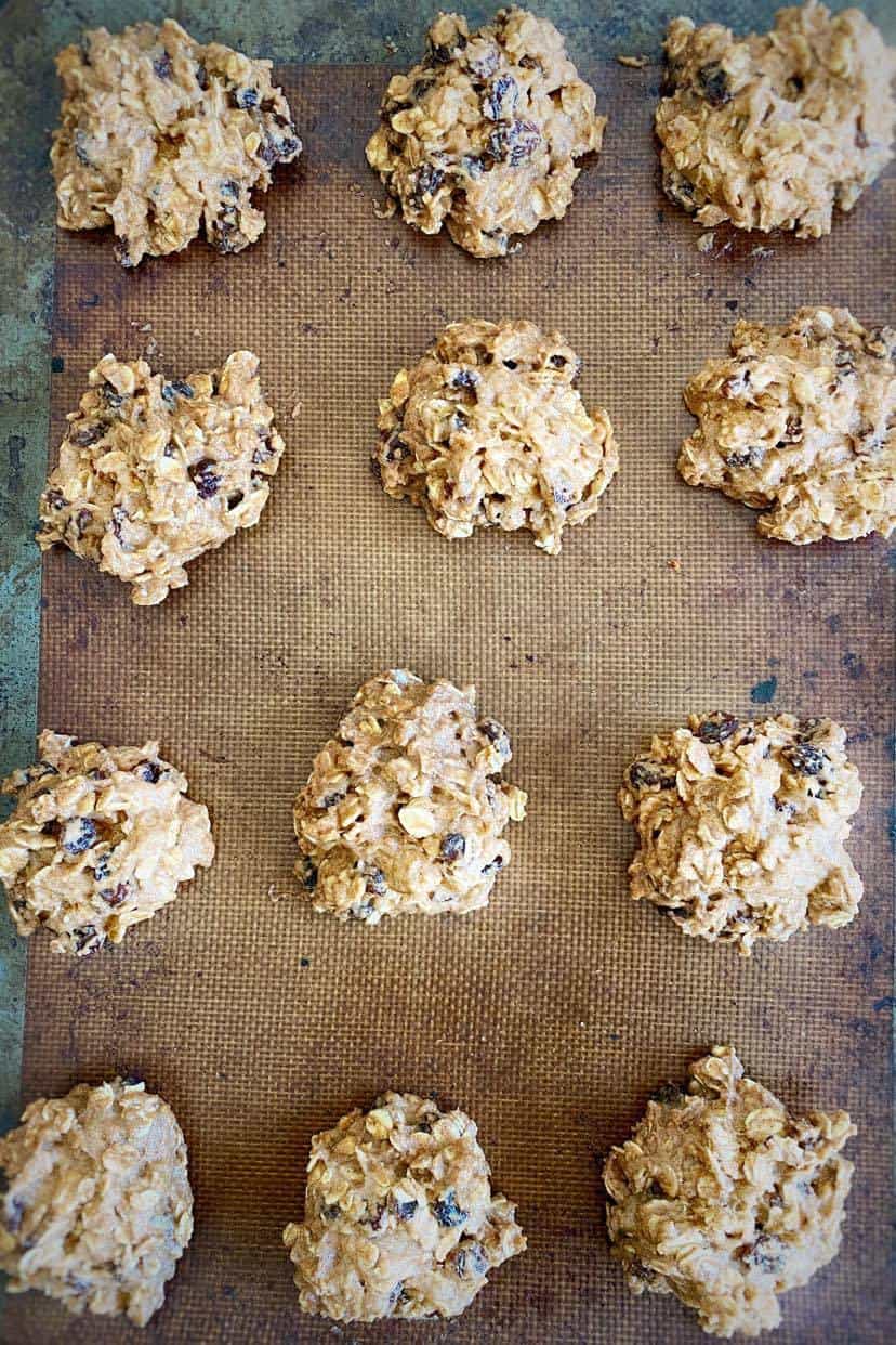 Vegan oatmeal raisin cookies uncooked on a baking sheet.