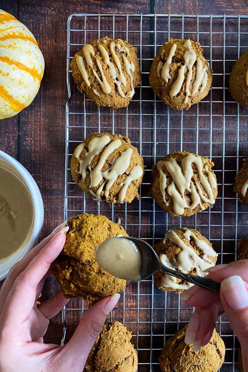 Hand adding maple glaze to vegan pumpkin cookies.