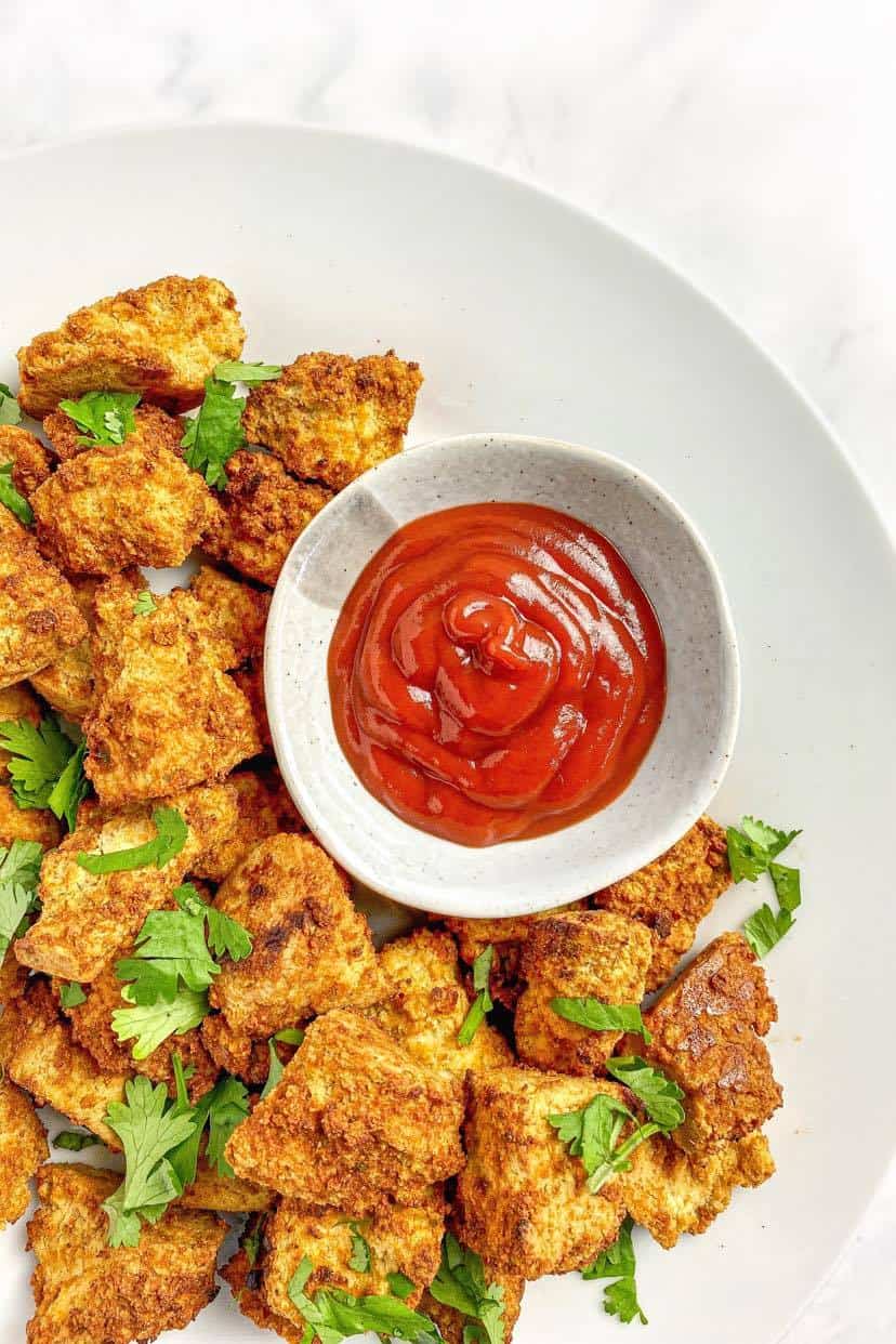 Air fryer tofu nuggets on a plate with ketchup.