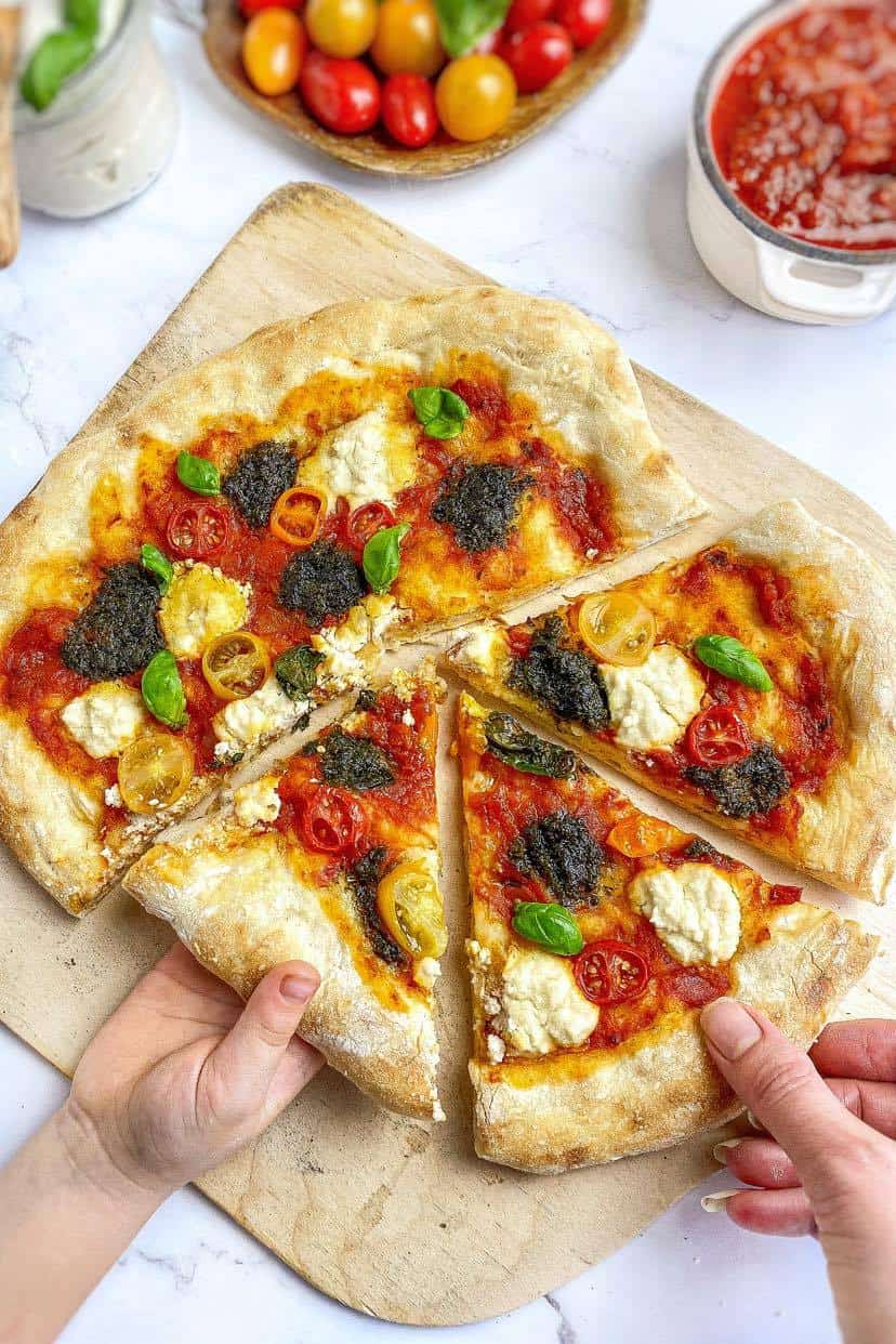 Pizza cut on a paddle with two hands taking slices.
