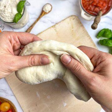 Hands stretching pizza dough.