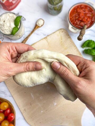 Hands stretching pizza dough.