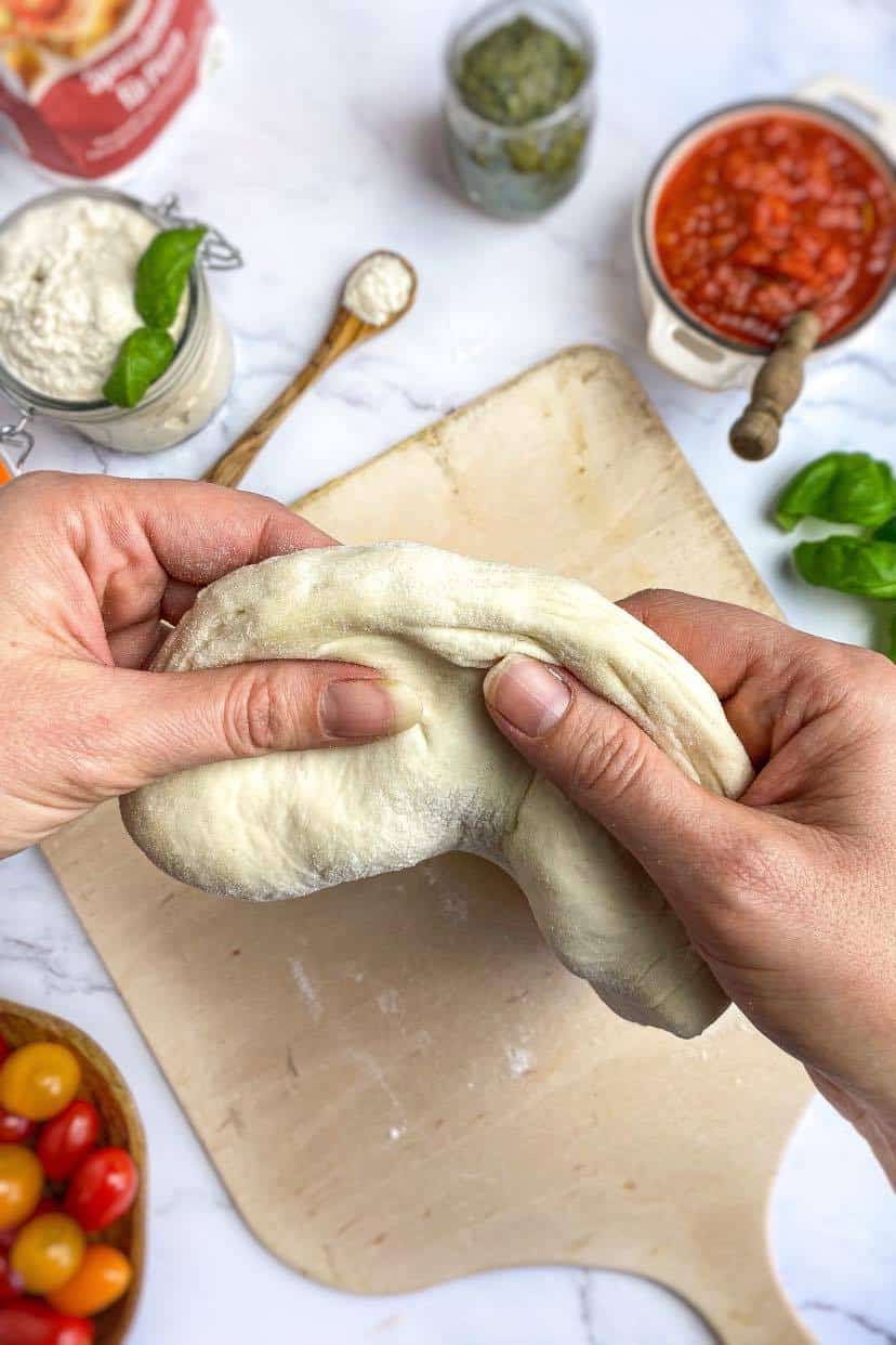 Hands stretching pizza dough.