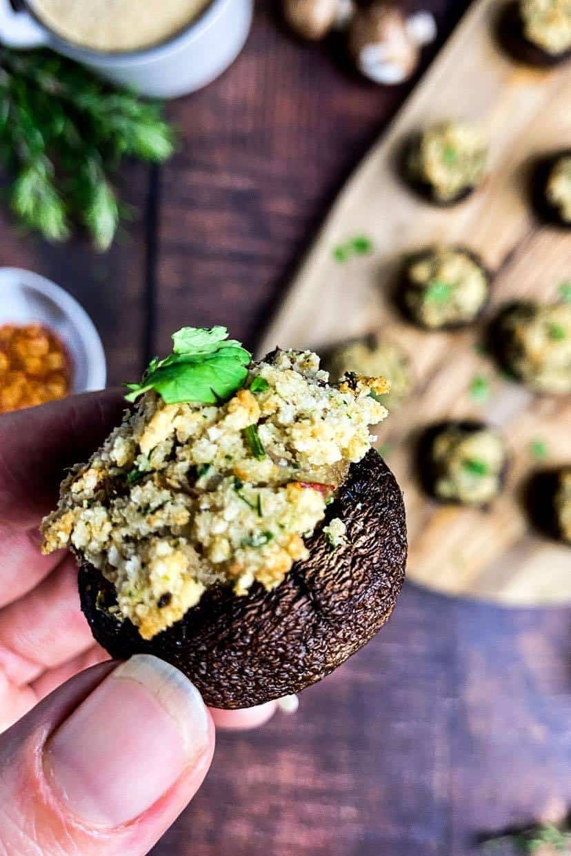 Hand holding a vegan stuffed mushroom.