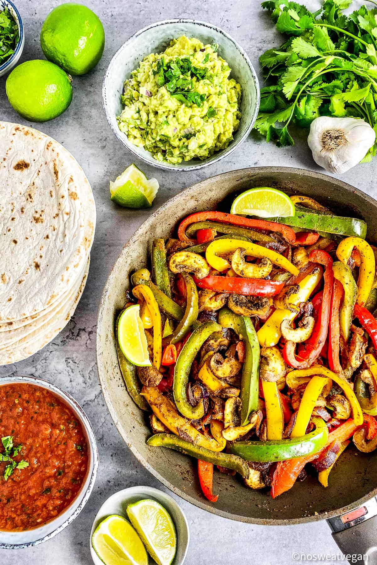 Vegan fajitas in a skillet next to tortillas.