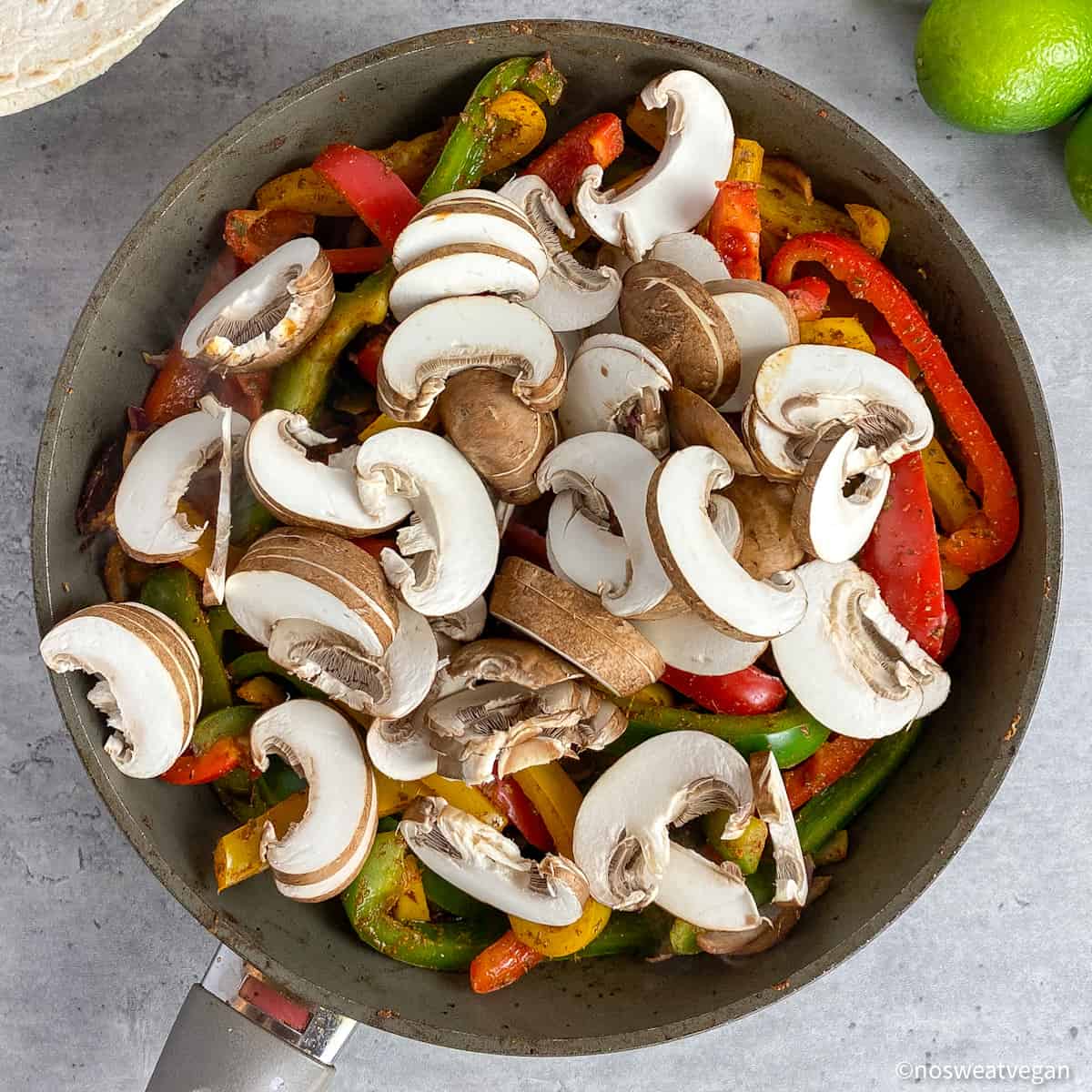 Mushrooms added to fajitas in a skillet.