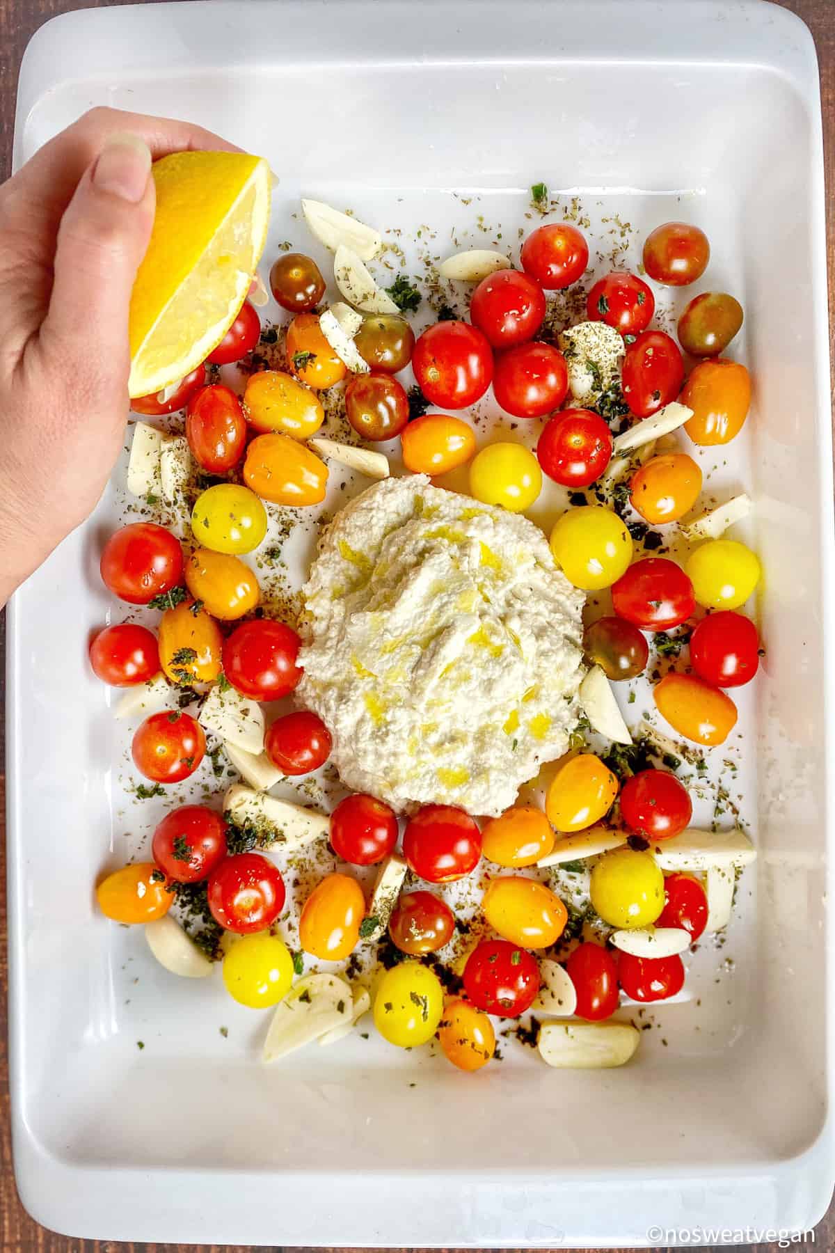 Almond ricotta, tomatoes, garlic, and seasoning in a baking dish.