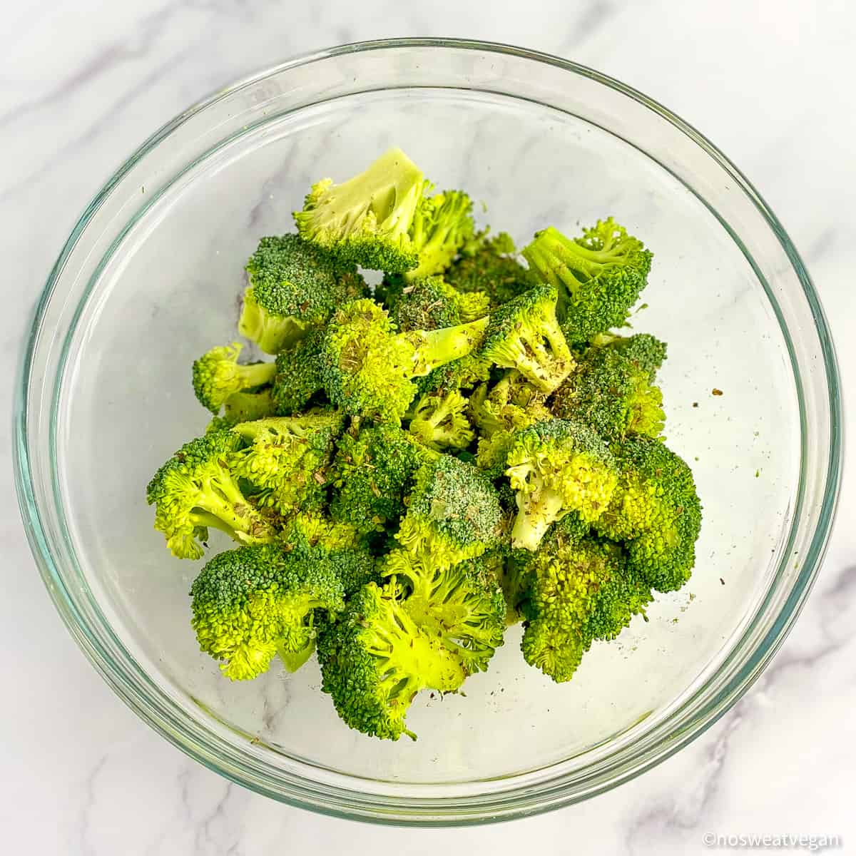 Fresh broccoli with seasonings in a bowl.