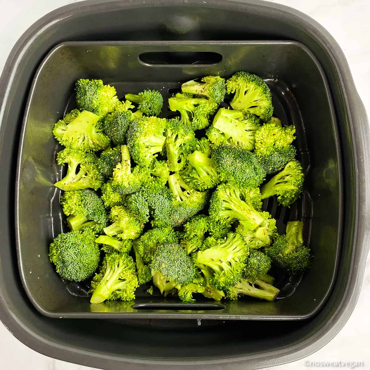 Fresh broccoli (uncooked) in the air fryer basket.