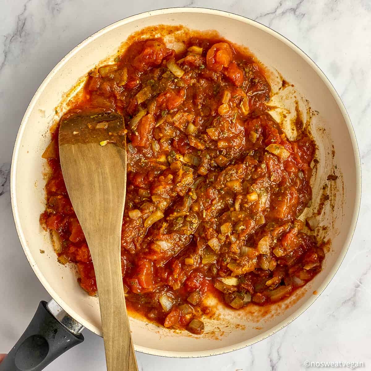 Tomatoes, spices, and onions in a skillet.
