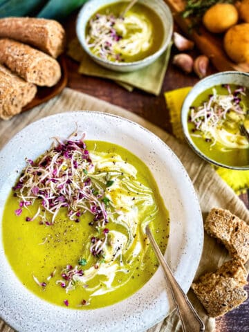 Vegan leek and potato soup in a bowl topped with vegan yogurt and microreens.