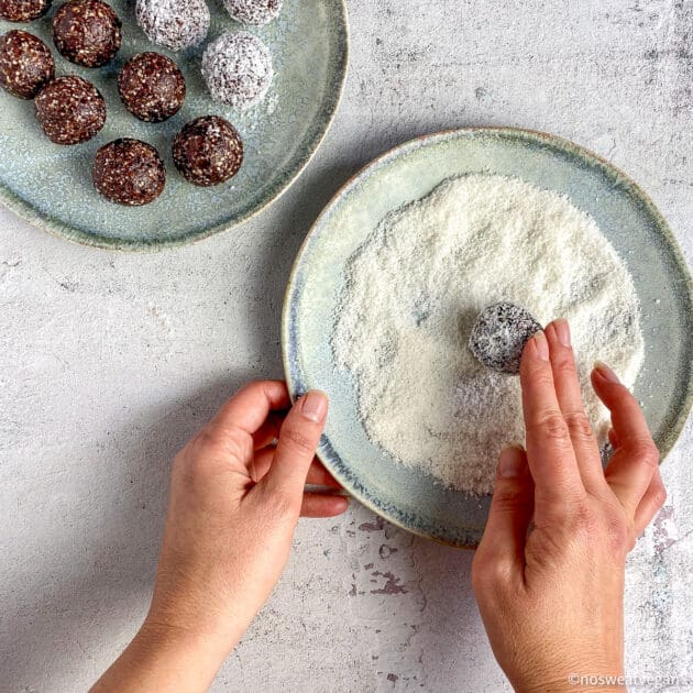 Hand rolling the bliss ball in desiccated coconut.