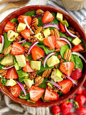 Spinach salad with strawberries, avocado, red onion, pecans, vegan bacon bits, and creamy balsamic dressing.