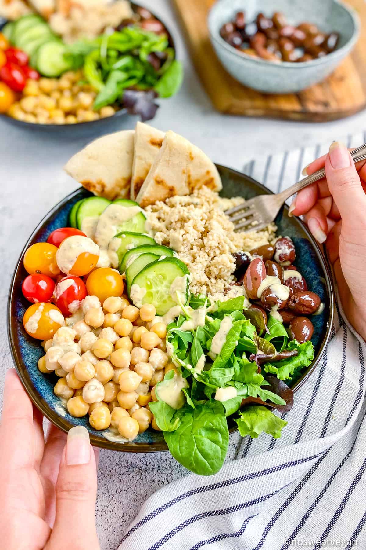 Hands holding chickpea couscous bowl.