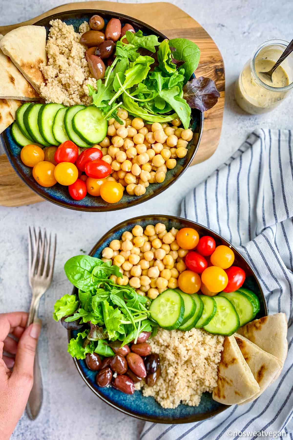 Two mediterranean buddha bowls and a hand holding forks.